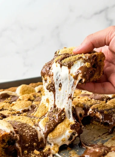 A close up of a gooey s'mores cookie bar square on a white plate.