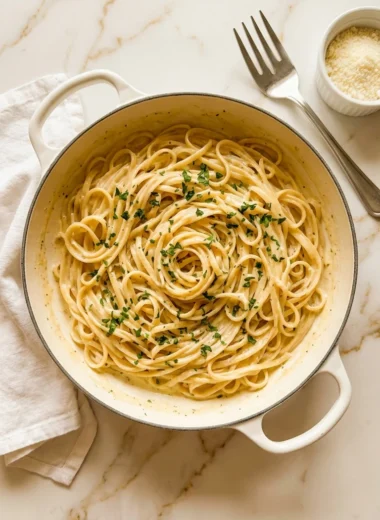 One Pot Creamy Garlic Pasta in a white ceramic bowl topped with Parmesan and parsley on white marble