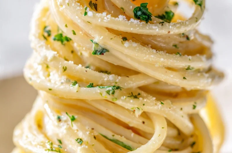 Extreme close-up vertical shot of One Pot Creamy Garlic Pasta in a white bowl showing silky cream sauce coating spaghetti strands