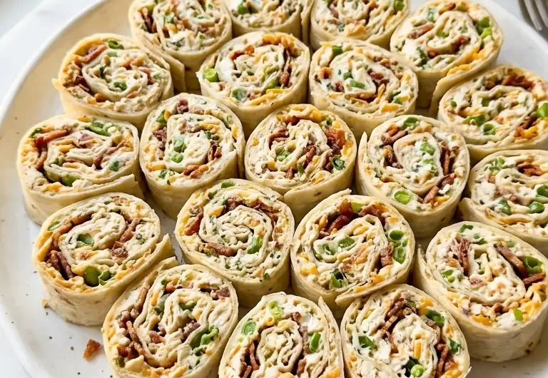 Close-up of crack chicken pinwheels arranged on a white ceramic platter showing creamy ranch swirls