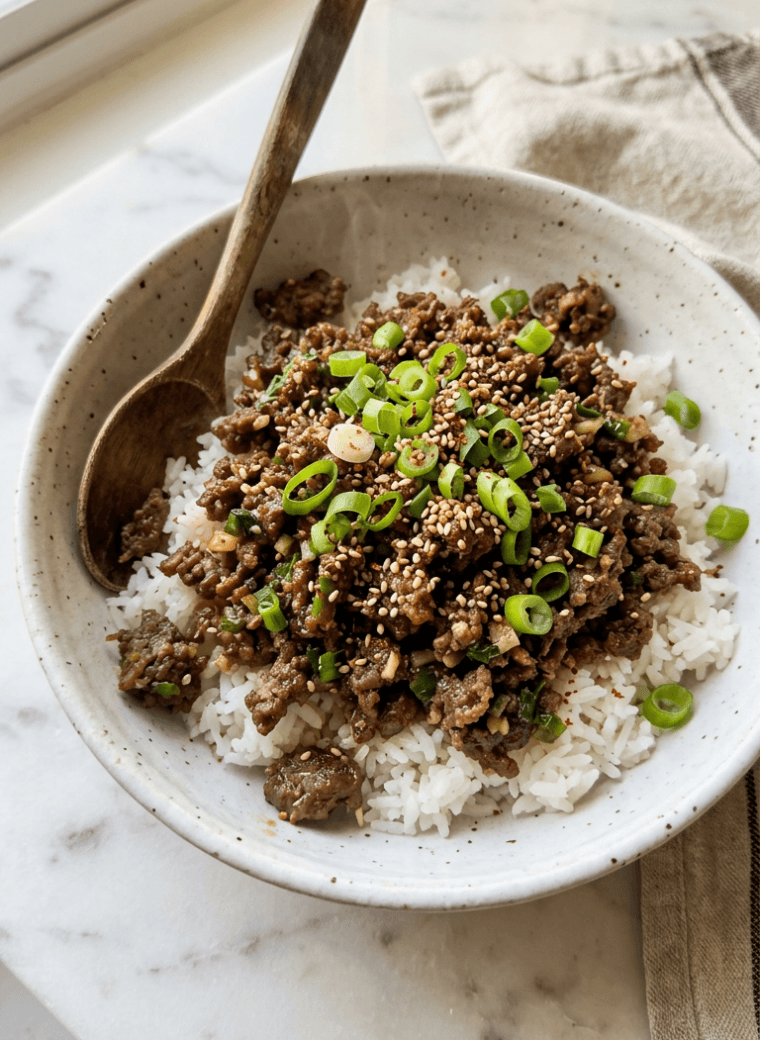 Korean ground beef bowl with glossy savory sauce over jasmine rice topped with sesame seeds