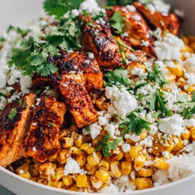 A finished tasty street corn chicken bowl ready to be eaten on a marble counter.