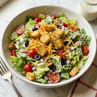 chopped salad Texas Roadhouse style in a white ceramic bowl with croutons and ranch dressing