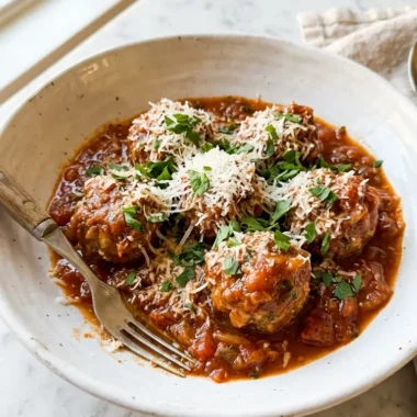 melt-in-your-mouth Italian meatballs in tomato sauce in a white ceramic bowl with parsley