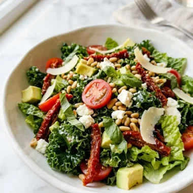 Close-up of a Marry Me Salad in a white ceramic bowl with kale, avocado, cherry tomatoes, feta, and pine nuts