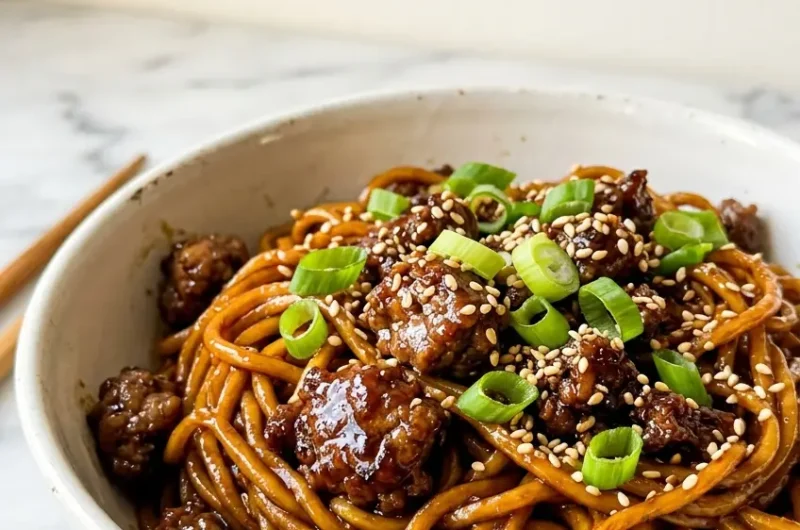 Pinterest pin image of sticky beef noodles in a white bowl with glossy sauce and spring onion topping