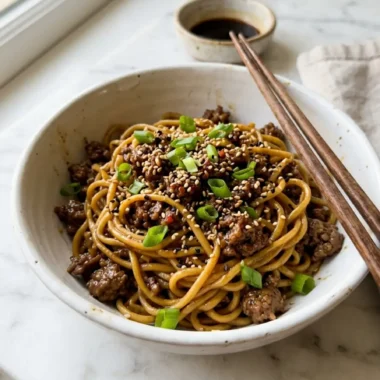 steaming bowl of Mongolian Ground Beef Noodles with green onions and sesame seeds