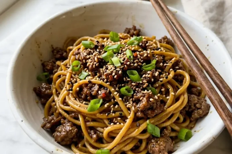 steaming bowl of Mongolian Ground Beef Noodles with green onions and sesame seeds