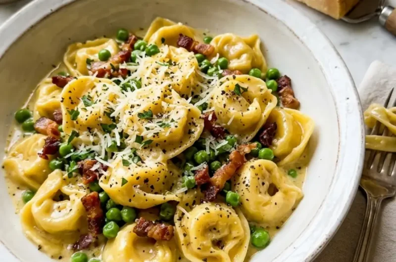 Tortellini Carbonara in white bowl with peas, pancetta, and black pepper