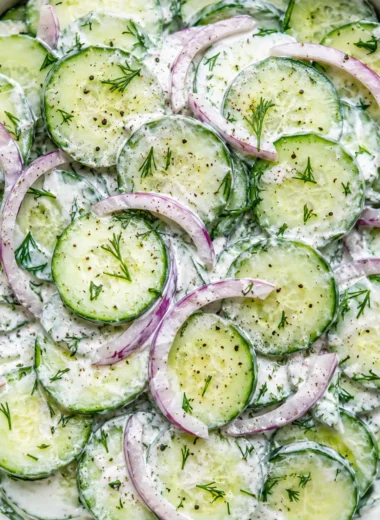 creamy cucumber dill salad in a white ceramic bowl with fresh dill and scallions