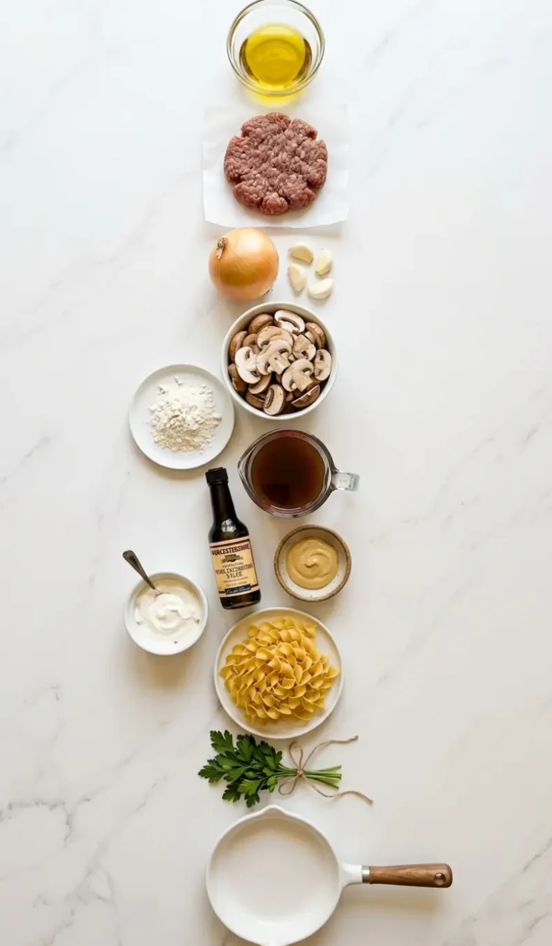 exploded view of 12 ingredients for easy ground beef stroganoff arranged on white marble